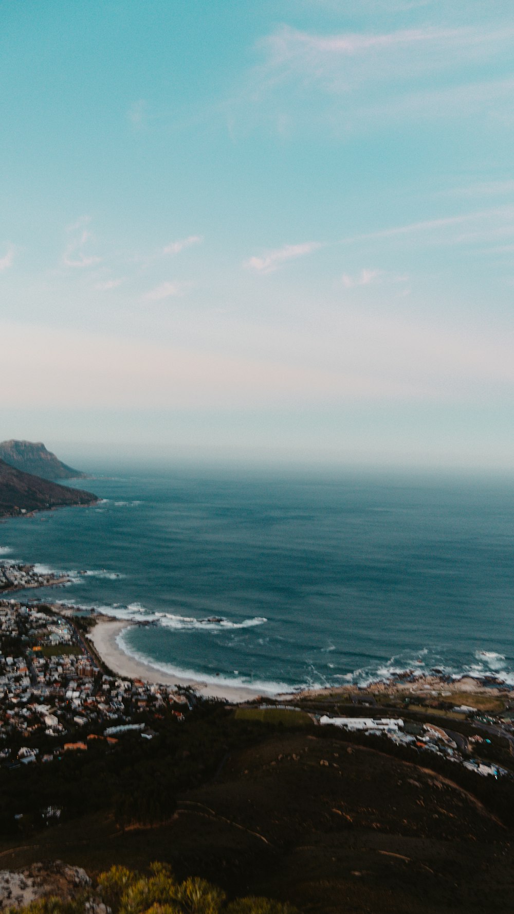 a view of a city and the ocean from a hill