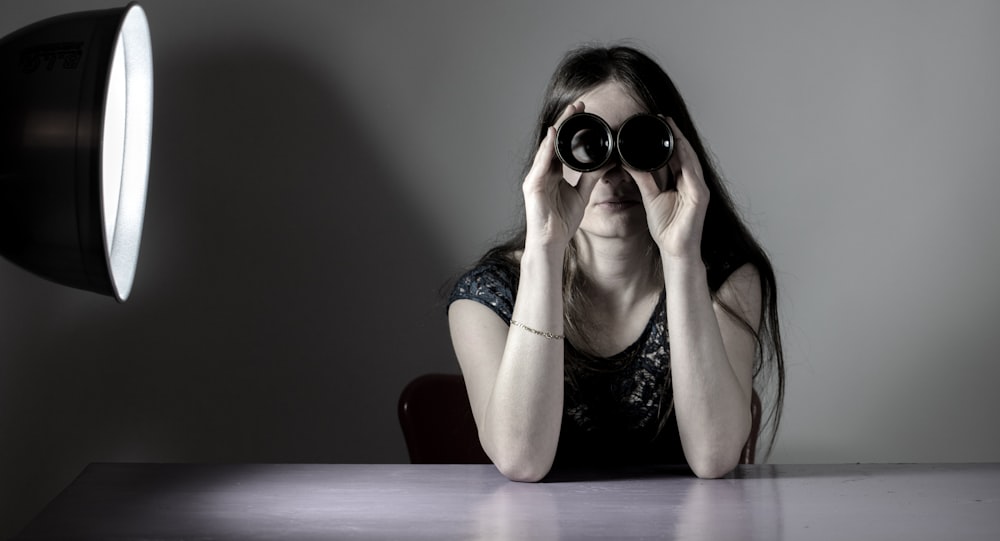 a woman sitting at a table with a camera in front of her