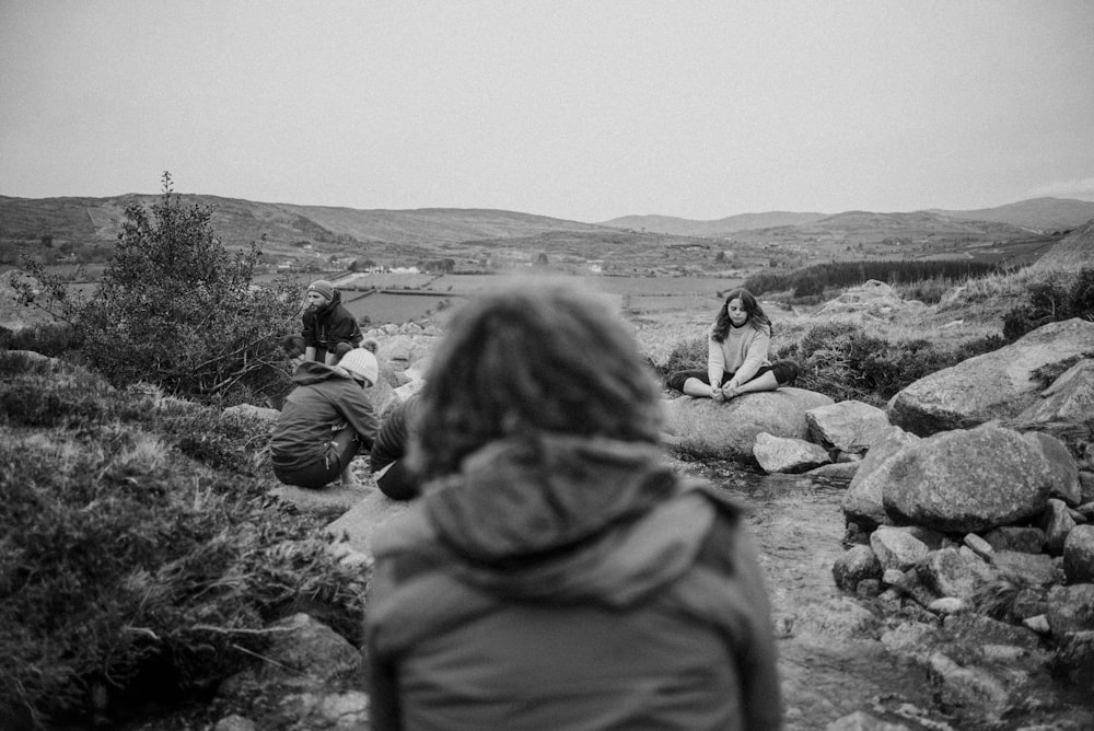 a group of people sitting on top of a rocky hillside
