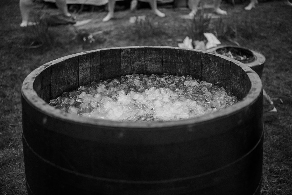 a barrel filled with ice sitting on top of a grass covered field