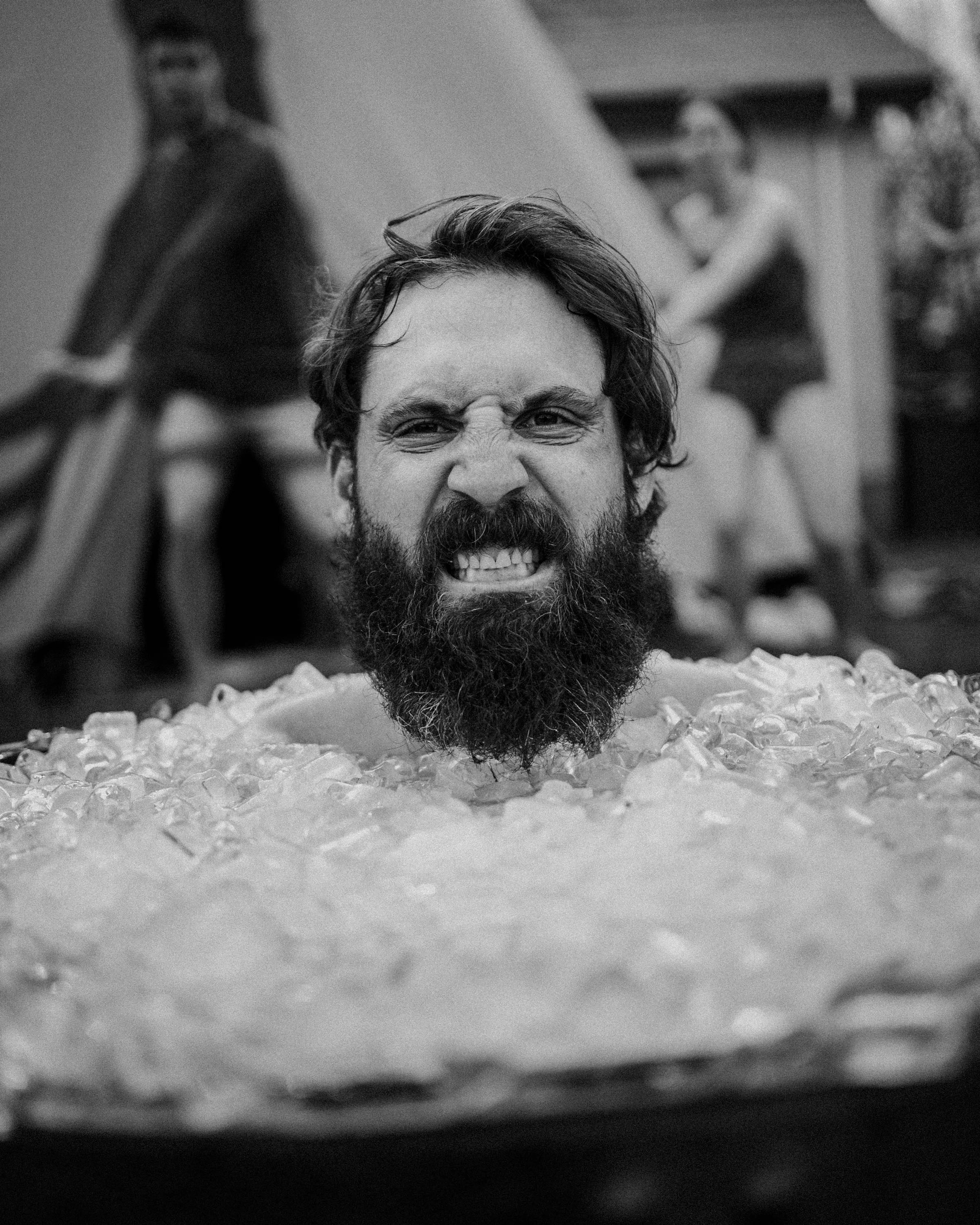 A man fully submerged to the shoulders in an ice-filled recovery tub, bracing against the cold.