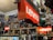 A cluttered room filled with various collectibles and memorabilia. Prominent Levi's signs are displayed among a dense arrangement of action figures, posters, and pop culture items such as Star Wars and music-related merchandise. Shelves are packed with an array of toys and models, creating a vibrant and chaotic visual atmosphere.