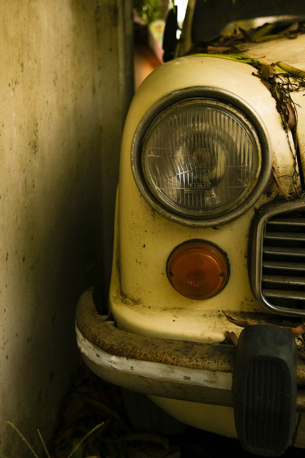 an old yellow car with a rusted out front