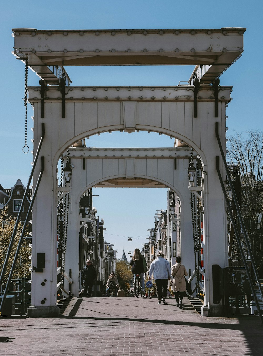 a group of people walking down a street under a bridge