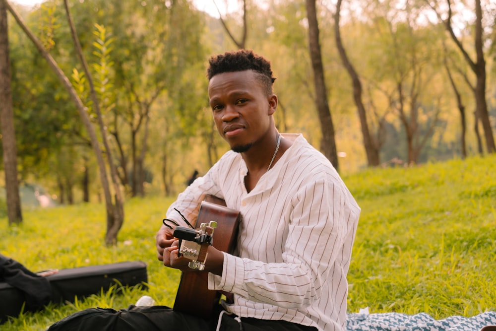 a man sitting on a blanket holding a guitar