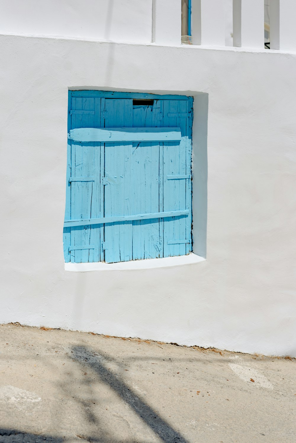 a white building with a blue window and a red fire hydrant