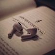 two white ear buds laying on top of an open book
