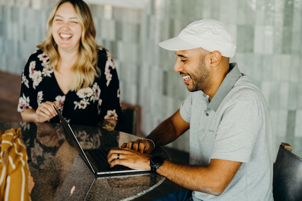 a man and a woman sitting at a table with a laptop