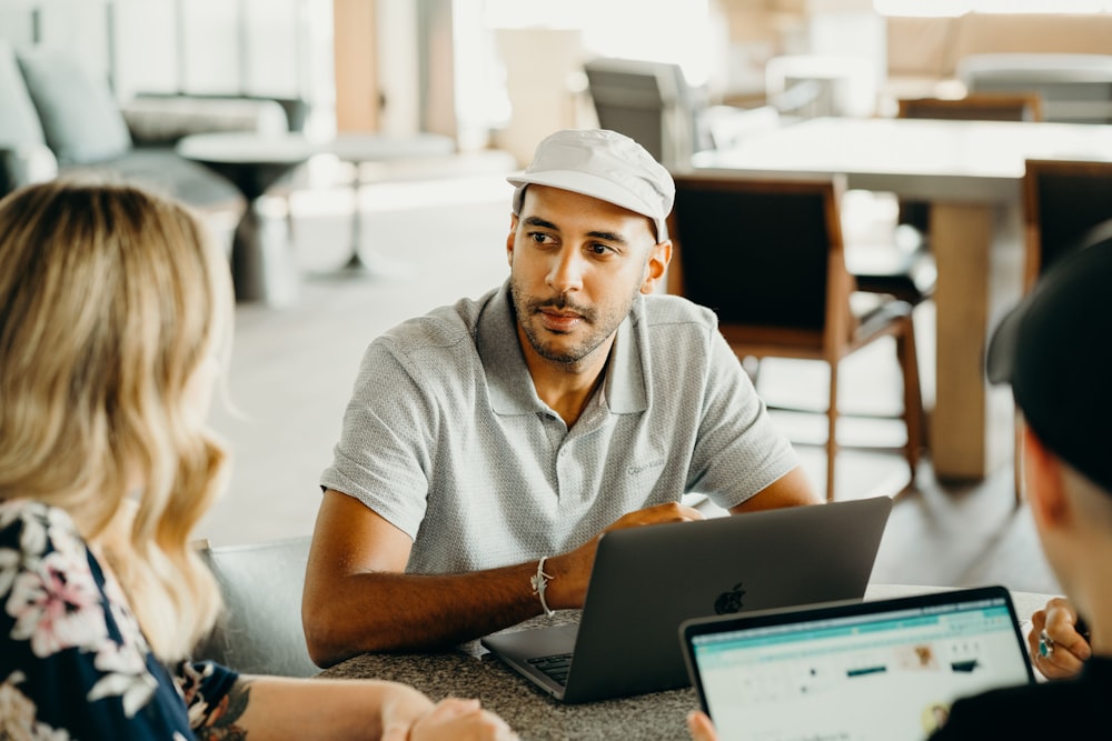 a man and a woman sitting at a table with laptops