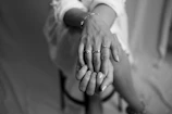 Soft-focus image of a model’s hand adorned with delicate gold rings resting on a deep blue velvet chair.