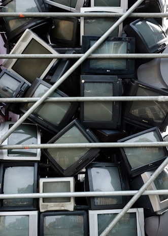 Stack of fixed TVs and microwaves ready for pickup in a bright repair shop.