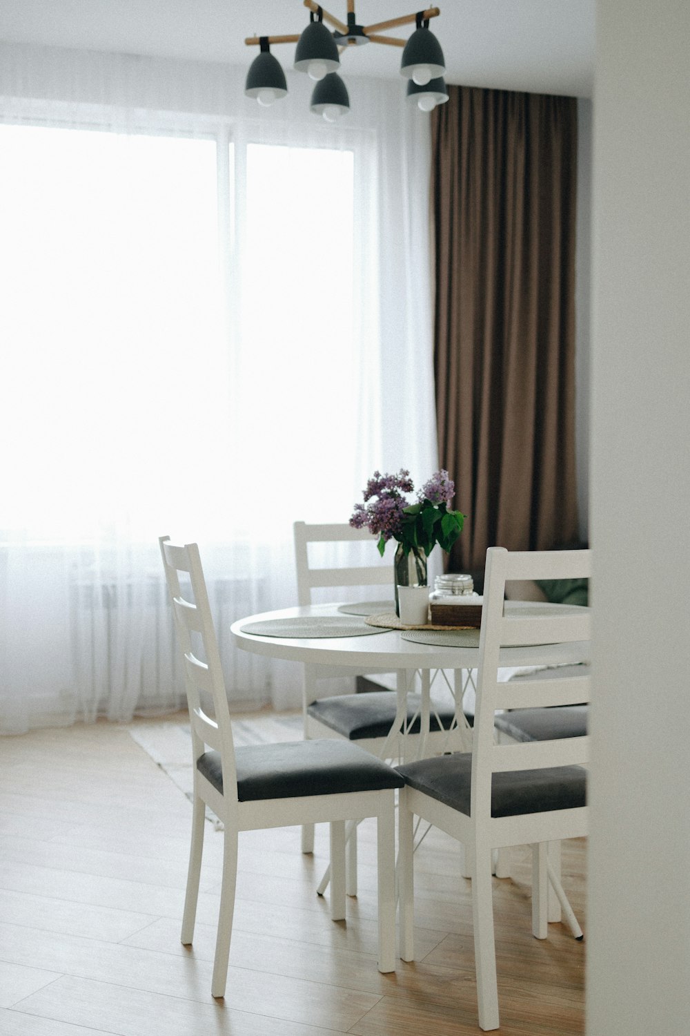 a dining room table with chairs and a vase of flowers