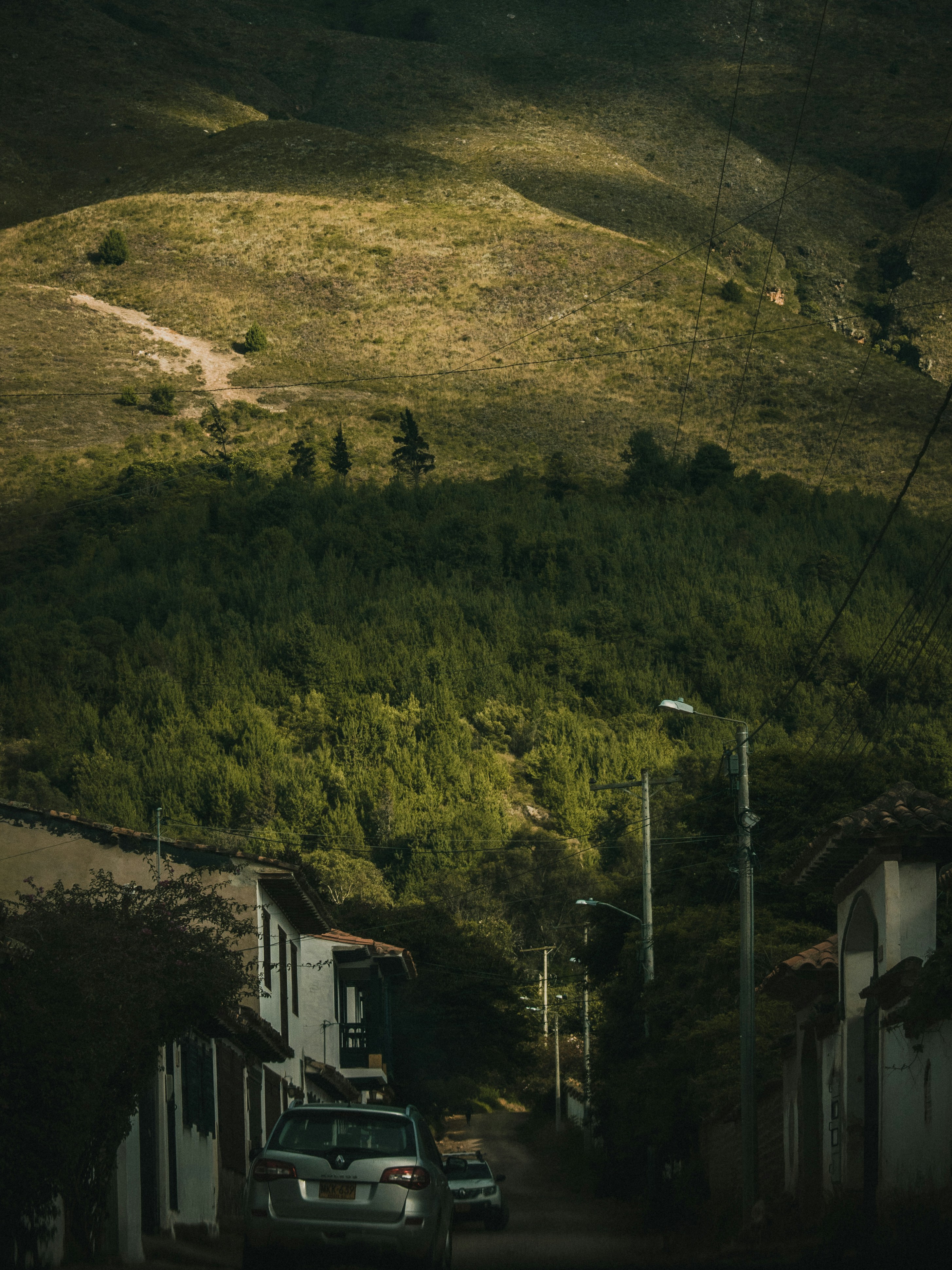 a car driving down a road next to a lush green hillside