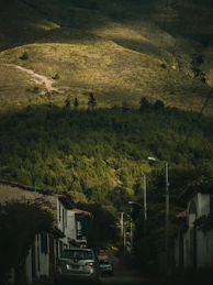 a car driving down a road next to a lush green hillside