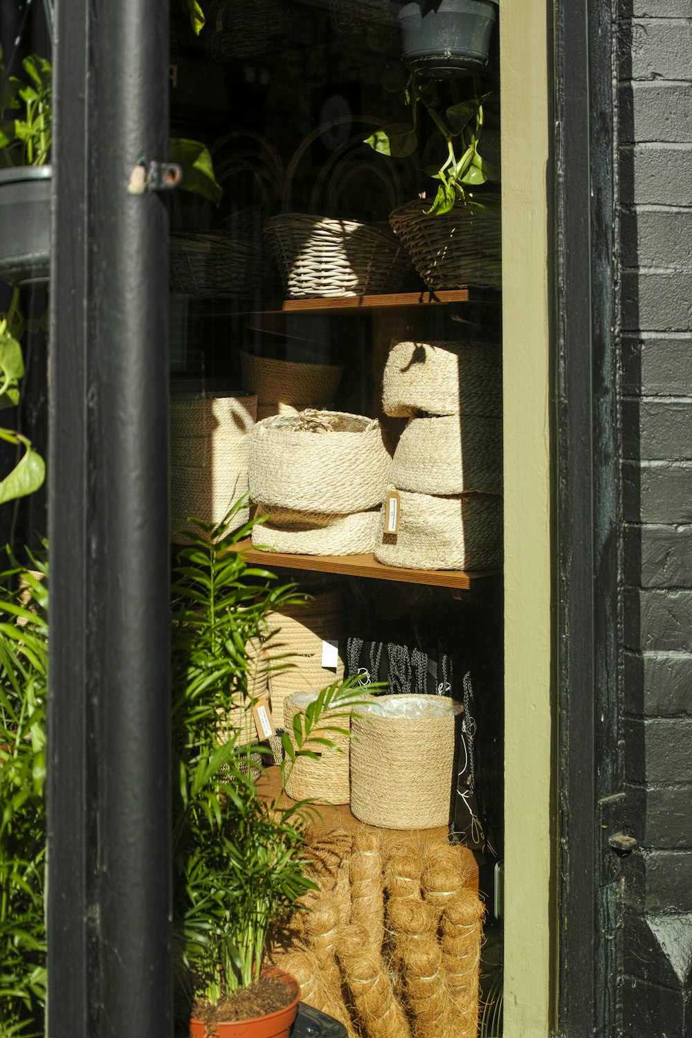 a shelf filled with baskets and plants in front of a window