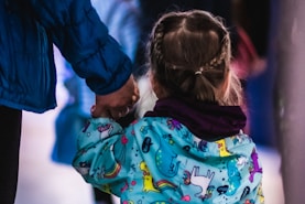 a little girl holding the hand of an adult