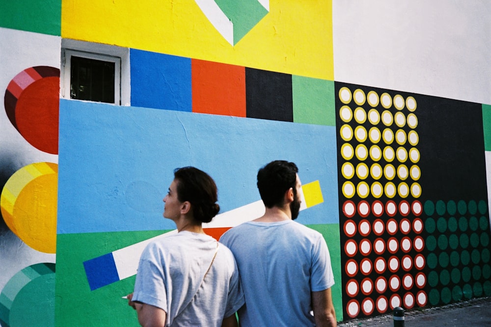 a couple of men standing in front of a colorful wall