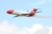A brightly colored aircraft with red and white markings is flying in a clear blue sky. The plane has the words 'Oil Spill Response' on its side and is releasing a mist or spray from its underside.