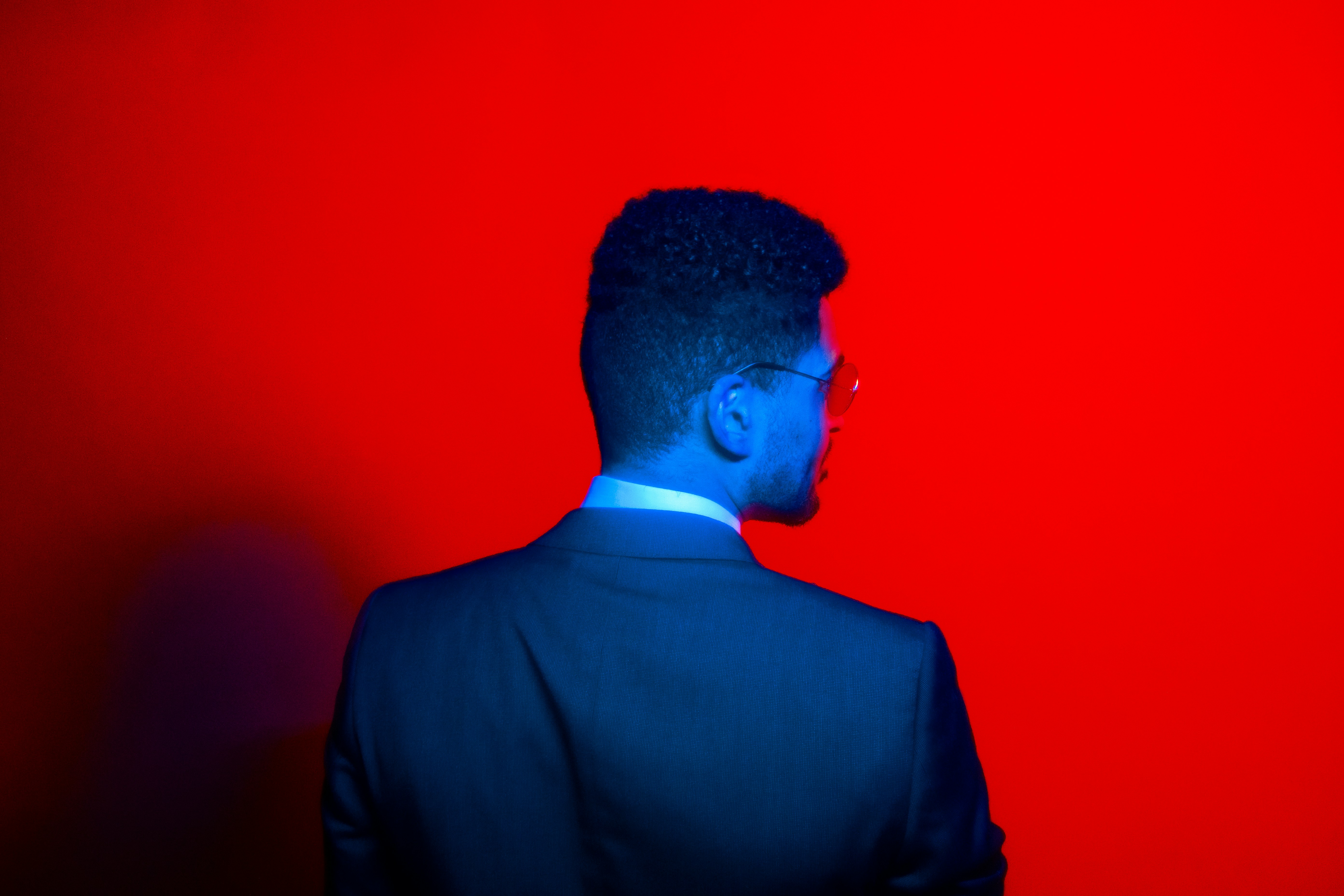 a man in a suit standing in front of a red wall