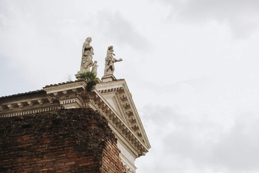 a tall brick building with statues on top of it