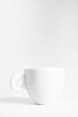 a white cup sitting on top of a white table
