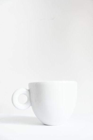 a white cup sitting on top of a white table