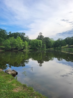 A serene outdoor shot of Carl reflecting beside a quiet lake, symbolizing inspiration and calm.