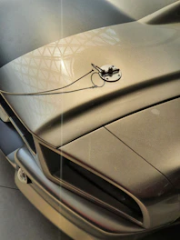 Close-up shot of a carbon fiber car hood with sleek metallic reflections under soft lighting.