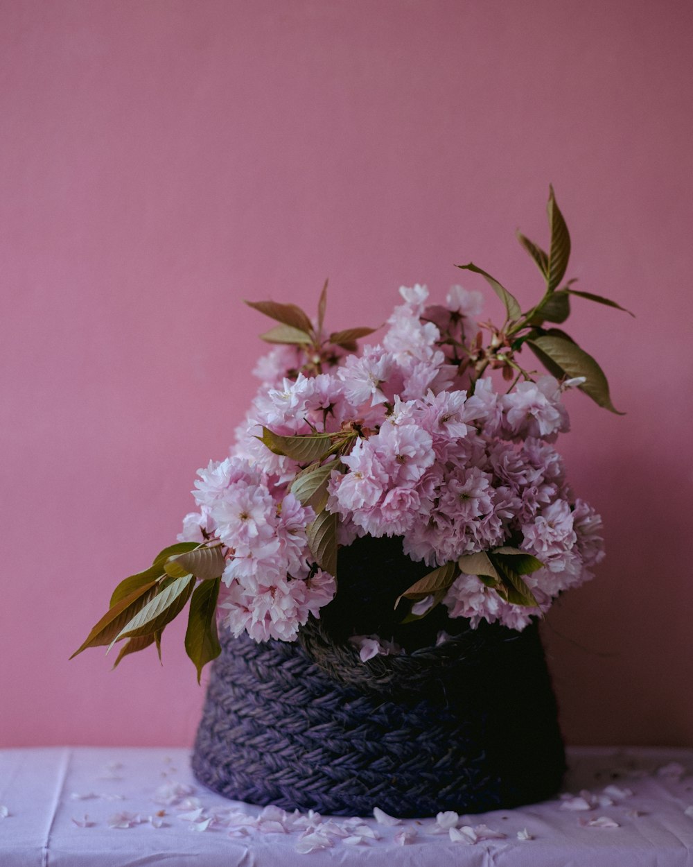 a black basket with pink flowers on a table
