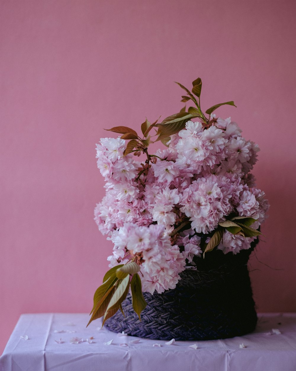 pink flowers in a black basket on a table