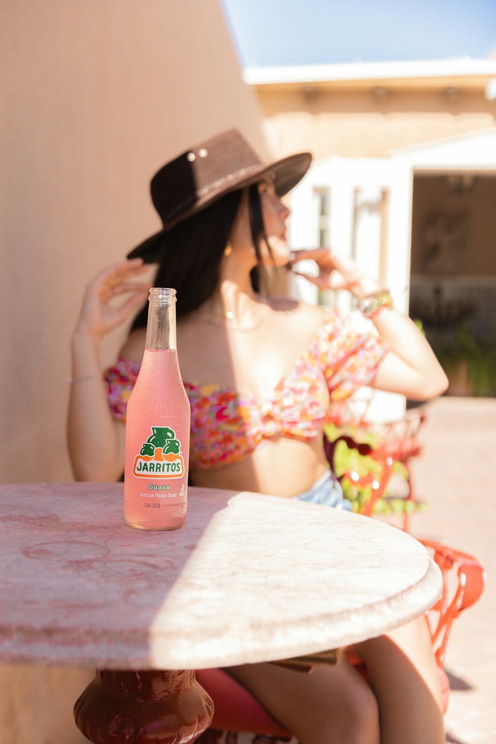 a woman sitting at a table with a bottle of beer