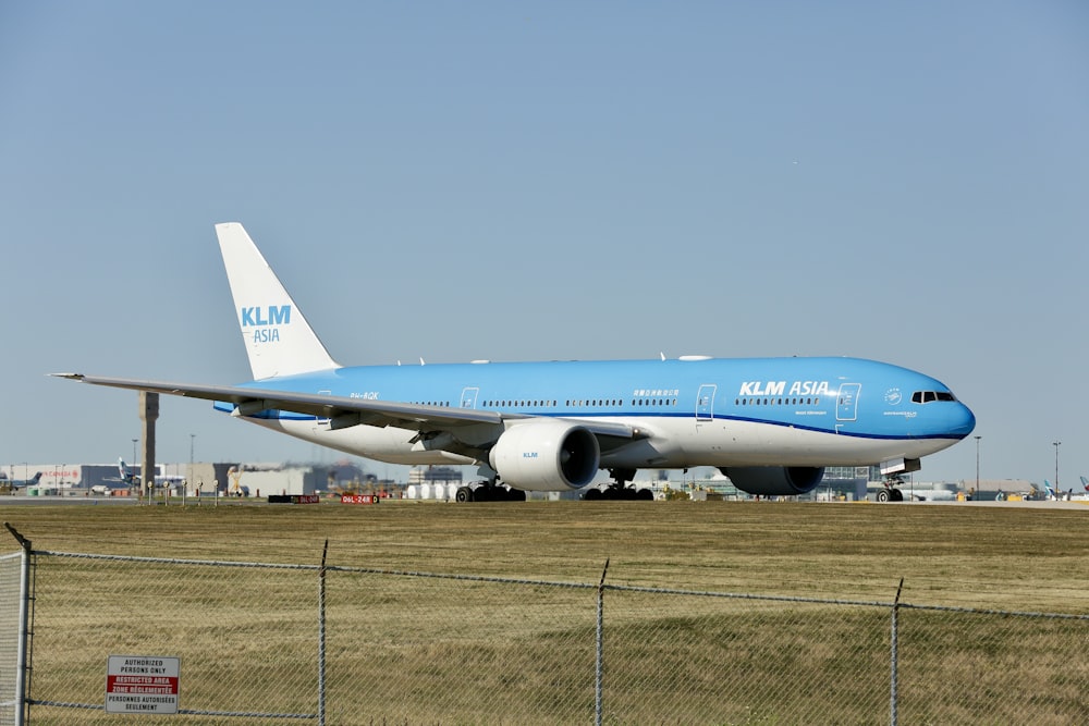 um grande jato azul e branco sentado no topo de uma pista de aeroporto
