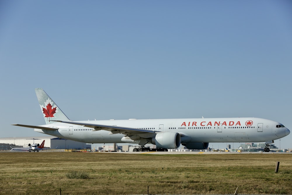 a large air canada jetliner sitting on top of an airport runway