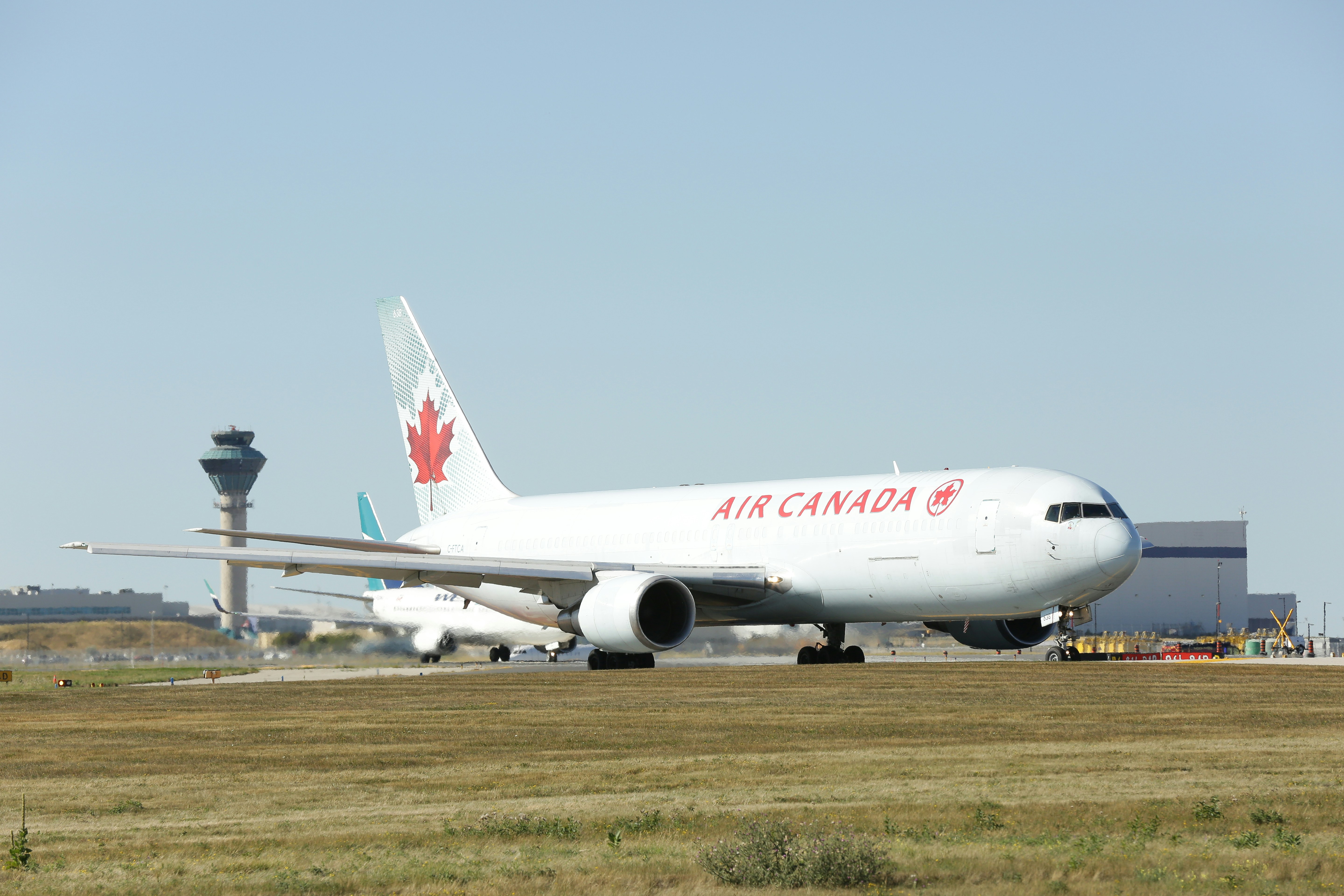 a large air canada jetliner sitting on top of an airport runway