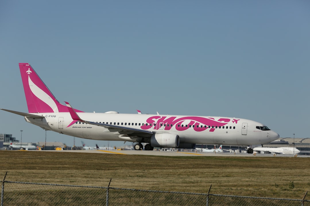 a pink and white airplane is on the runway,