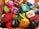 A collection of colorful cartoon figurines arranged randomly. The figures include a variety of characters with different facial expressions and accessories. The figurines are made of plastic and feature playful designs and bright colors.