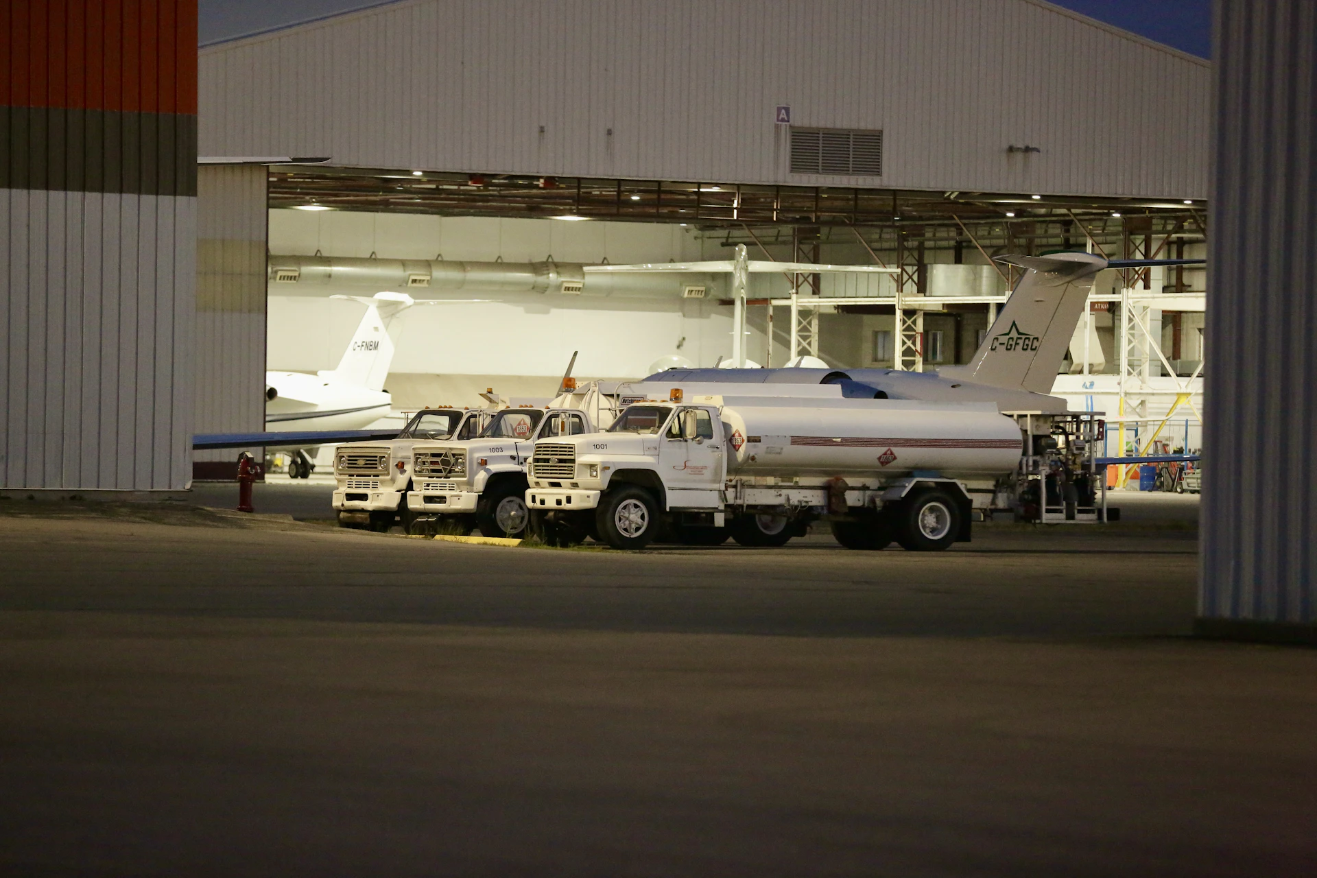 two trucks parked in front of a hangar