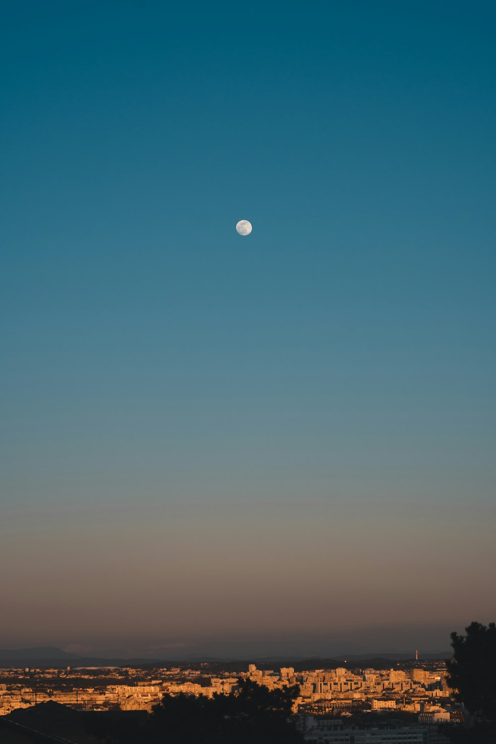 a full moon is seen in the sky above a city