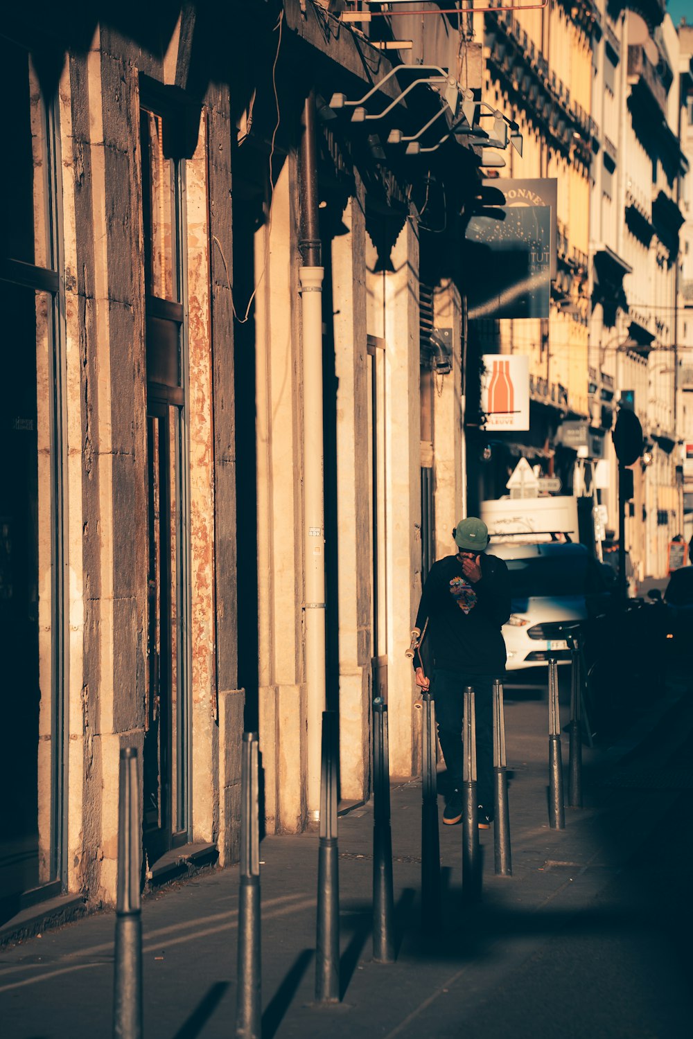 a man walking down a street next to tall buildings