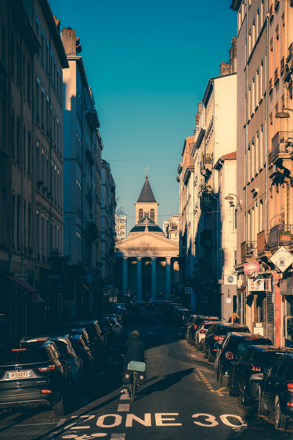 a city street lined with tall buildings and parked cars