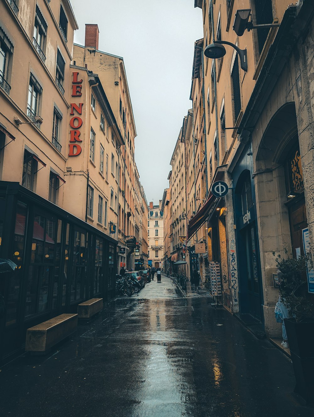 a wet street in a city with tall buildings