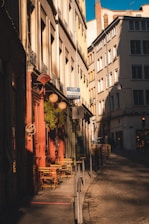 A cozy café terrace in a narrow European street bathed in golden afternoon light.
