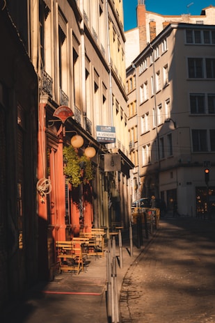 A cozy café terrace in a narrow European street bathed in golden afternoon light.