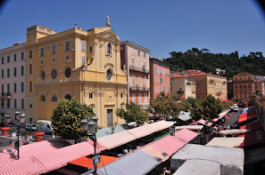 A vibrant street in Kotor with colorful buildings and lively market stalls under a bright blue sky