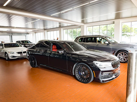 A friendly car dealership showroom with red, black, and white cars lined up under warm lighting.