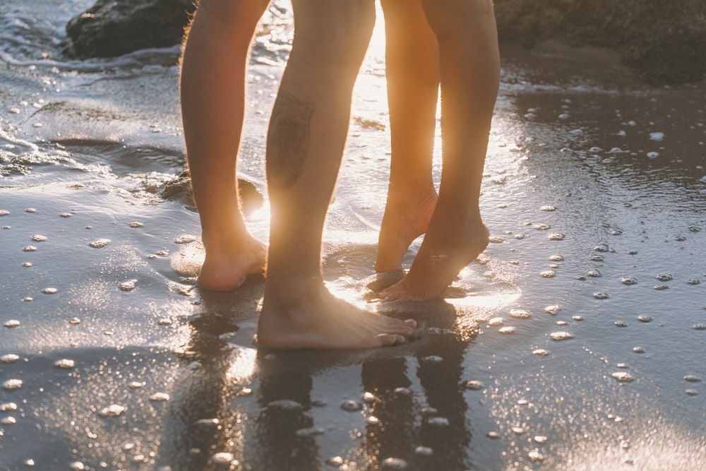 a couple of people standing on top of a sandy beach