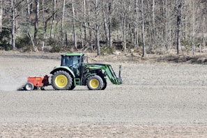 Tractor working on a green agricultural field during sunrise