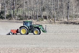Tractor working on a green agricultural field during sunrise