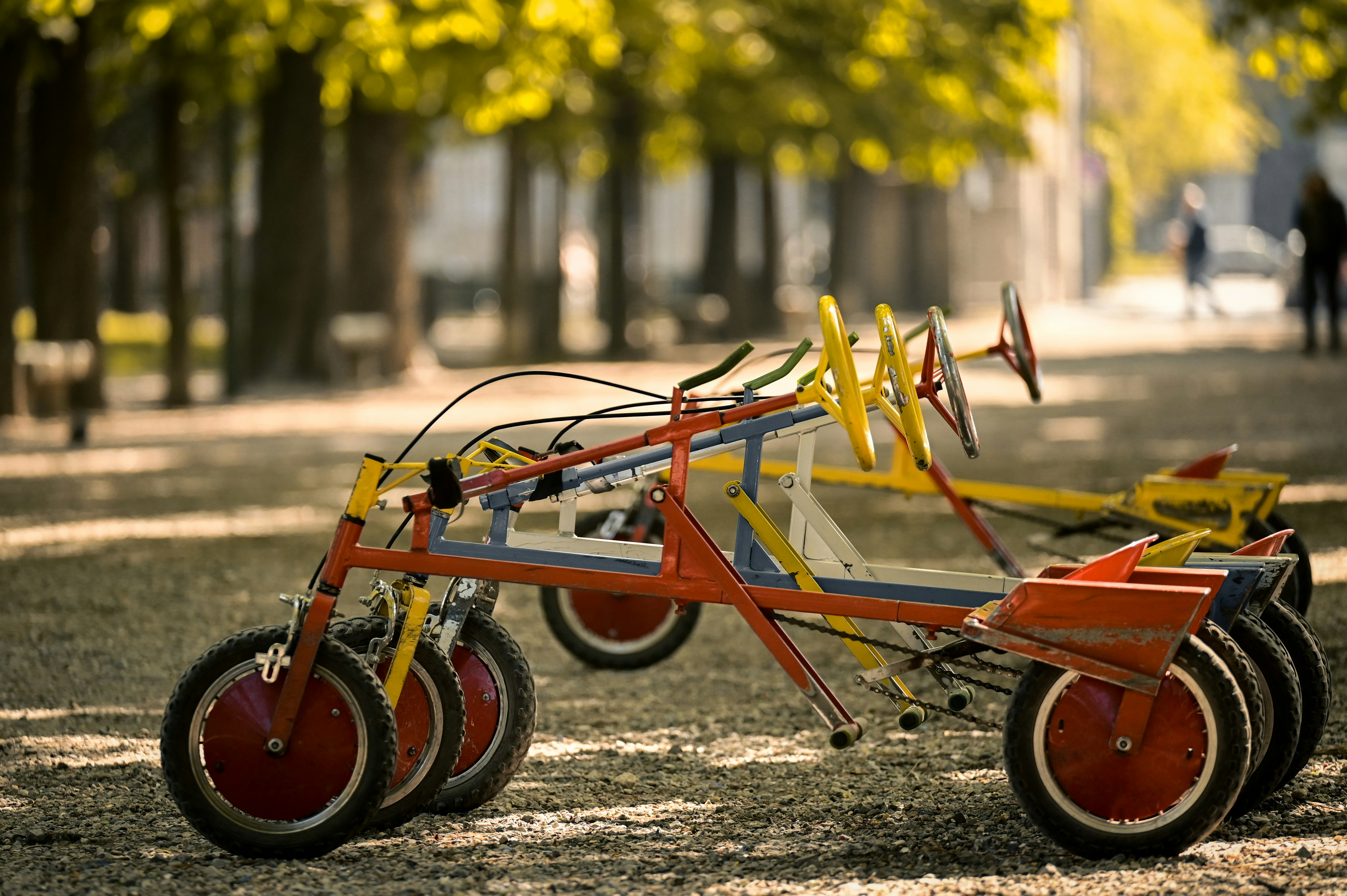 a row of red and yellow tricycles sitting on top of a grass covered