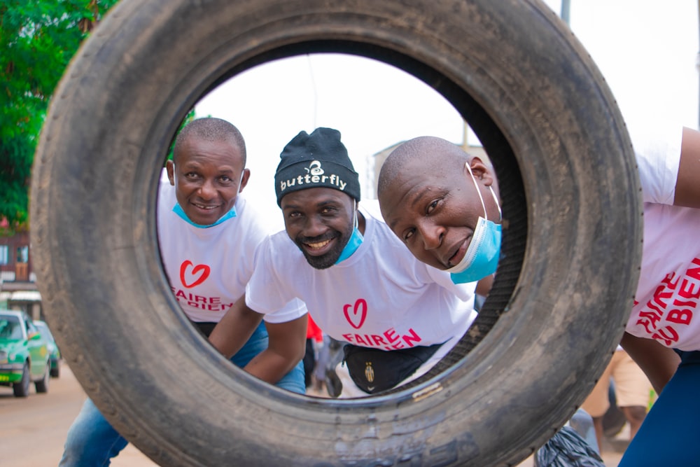 a group of men standing next to each other in front of a tire